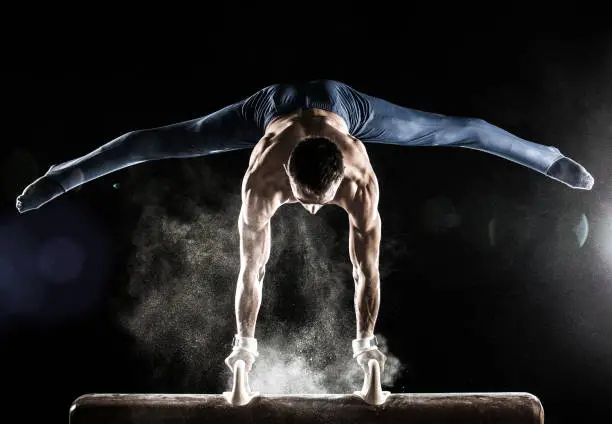 Male Gymnast doing handstand on Pommel Horse