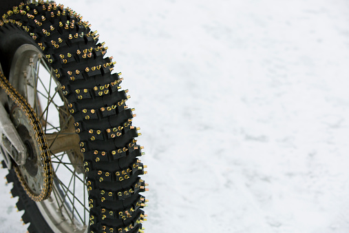 A close up view of a rear motorcycle tire with metal studs for riding on the ice and snow in the winter. 