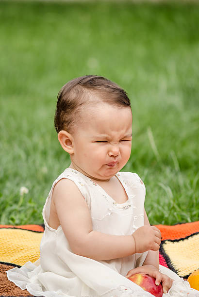 милая маленькая девочка ест яблоко с кислый - apple eating little girls green стоковые фото и изображения