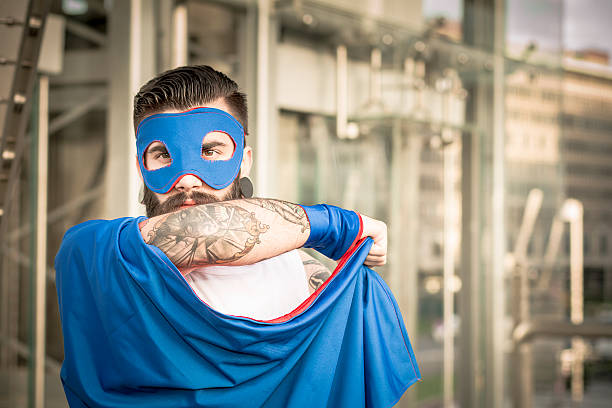 Hipster superhero in action Portrait of Young man (hipster style) with big earring and full beard wearing a superhero costume in action holding his mantle. cosplay stock pictures, royalty-free photos & images