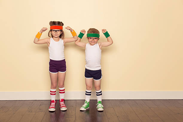 Workout Buddies Flexing Muscles A boy and girl dressed as 80s nerds are ready to sweat to stay fit during this workout. Flex your biceps for ultimate self confidence. eccentric stock pictures, royalty-free photos & images