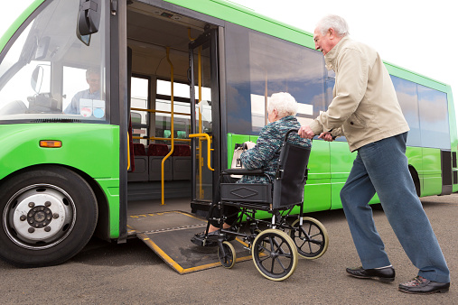 Senior couple getting on bus via wheelchair ramp.