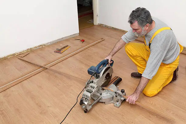 Worker cut wooden batten for laminate floor,  floating wood tile