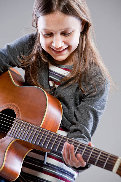 istock little girl playing acoustic guitar 532471211