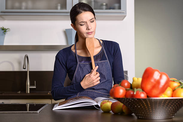 istock Woman Holding Ladle While Reading a cookbook 532506399