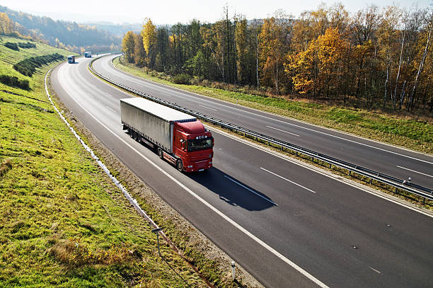 istock The highway between forests in fall colors, three trucks 532517649