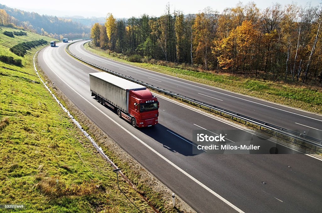 The highway between forests in fall colors, three trucks The highway between deciduous forests with leaves in fall colors, the highway ride three trucks, view from above 2015 Stock Photo