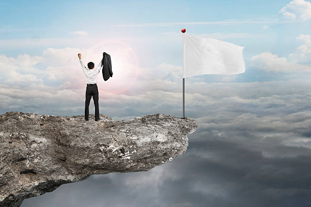 istock man cheering on cliff with blank flag and sunlight cloudscapes 532518269