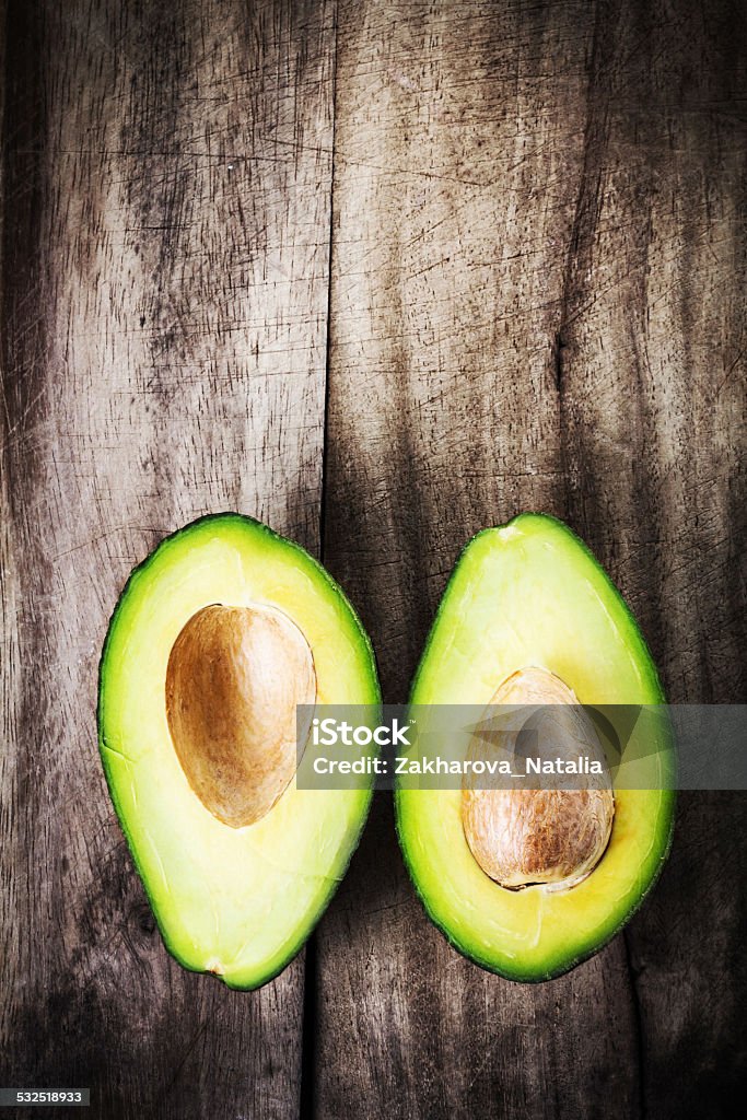 Fresh Avocado sliced over vintage wooden background close up. Fresh Avocado sliced over vintage wooden background close up. Ripe green avocado fruit on wood board. Hass Avocado Stock Photo