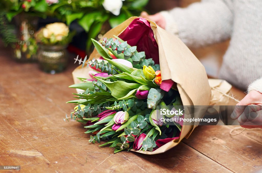 Beautiful bouquet ready for presentation Cropped shot of a pretty floral bouquet being completed on a wooden counter top Bouquet Stock Photo