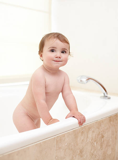 Bath time is over An adorable baby girl climbing out of the bath girls bath stock pictures, royalty-free photos & images