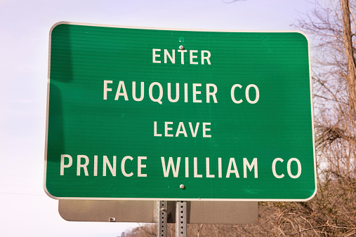 Green road sign in Virginia showing the border between Fauquier and Prince William Counties