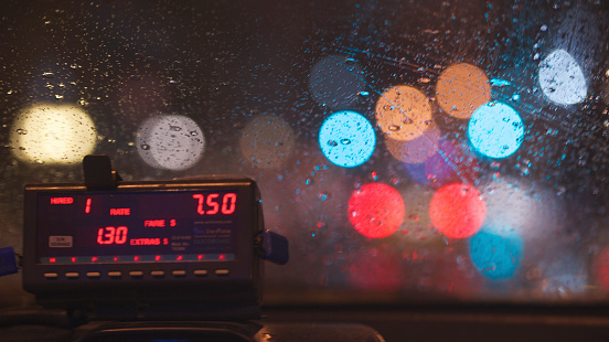 View of taxi dashboard and meter with colorful city bokeh lights.