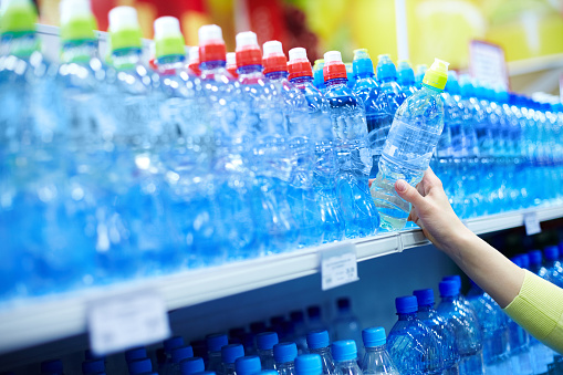 Close-up of female choosing good mineral water in a shop