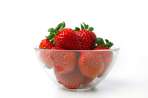 Strawberries in a glass bowl isolated on white.
