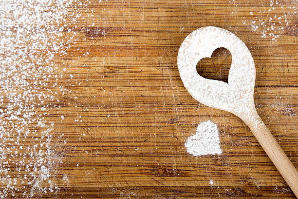 Heart hole spoon on the wooden pastry board - baking background