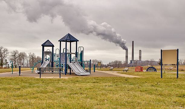 plac zabaw z fabryki smokestack pod palmami zanieczyszczeń w tle - toxic substance fumes environment carbon dioxide zdjęcia i obrazy z banku zdjęć