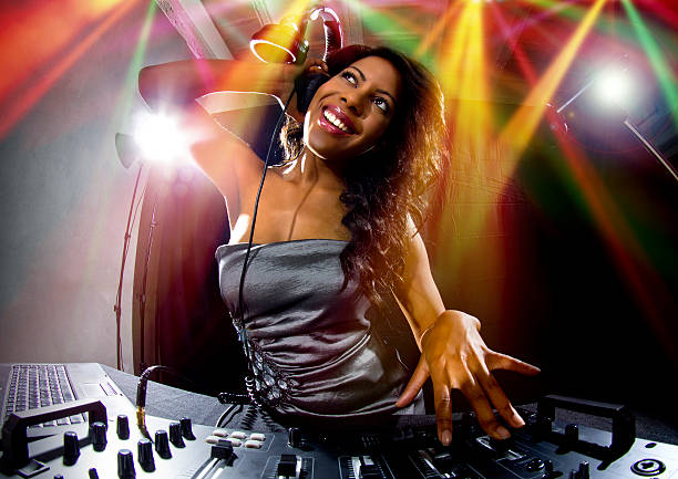 Black Female DJ in a Nighclub Party Playing Music Stock photo of a young african american female dj playing music at a party.  She is using mixers.  The party host is listening through headphones and looks energetic.  She might be at a nightclub or a disco. The image depicts the music and entertainment industry. diva stock pictures, royalty-free photos & images