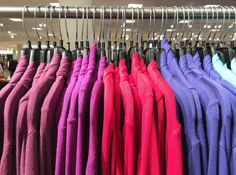 Colorful sweaters on a clothing rack.   Photographed with an iPhone 6.