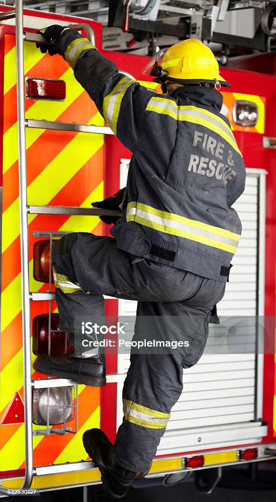 Manning the fire engine Shot of a fireman climbing the ladder of his firetruck 2015 Stock Photo