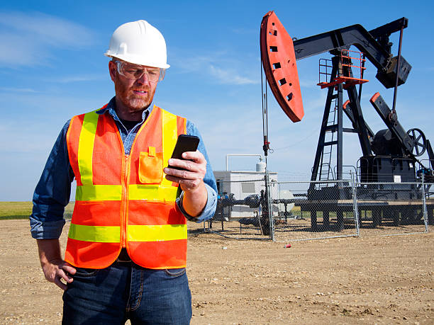 telefono intelligente di ingegnere di petrolio e tecnologia - oil pump oil industry alberta equipment foto e immagini stock