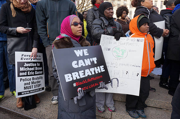 We Can't Breathe Washington DC, USA-December 13, 2014: These protesters are protesting police brutality at a protest led by Reverend Al Sharpton on Pennsylvania Avenue in Washington DC. This woman is bearing a sign protesting the strangling death of Eric Garner by police in Staten Island New York.  Recently the deaths of Michael Brown, Eric Garner and Tamir Rice have upset the black community. i cant breathe stock pictures, royalty-free photos & images