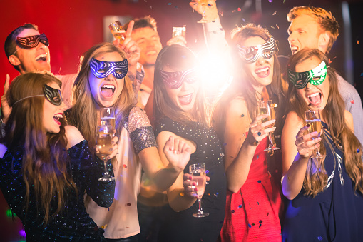 Friends in masquerade masks drinking champagne at the nightclub
