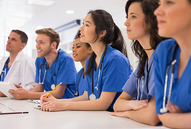 Medical students listening sitting at desk stock photo