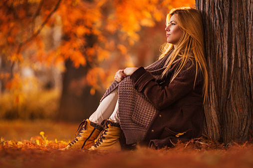 Pensive woman sitting in nature and looking away.