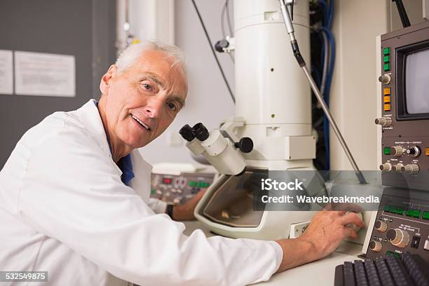 Biochemist Using Large Microscope And Computer Stock Photo - Download Image Now - 2015, 70-79 Years, Active Seniors