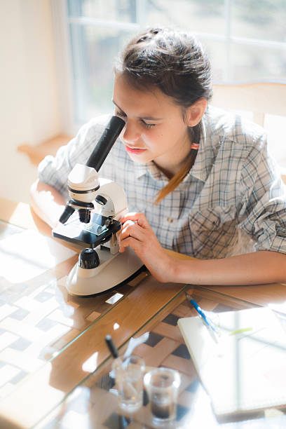 istock Teenage girl make homework scientific project with microscope 532550656