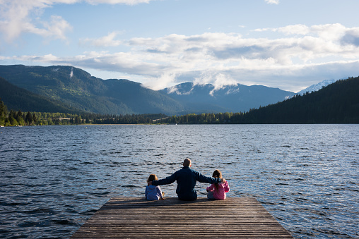 Father and daughters bonding by the lake