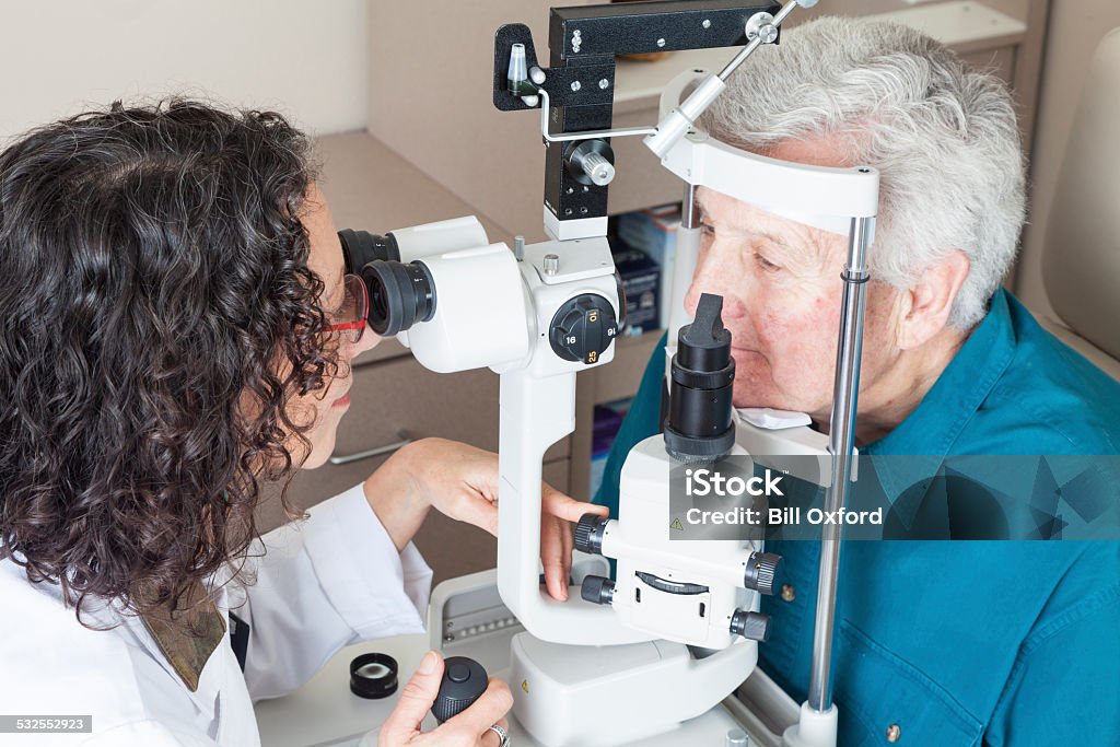 Optometrist with senior patient Optometrist giving eye exam to senior patient 2015 Stock Photo