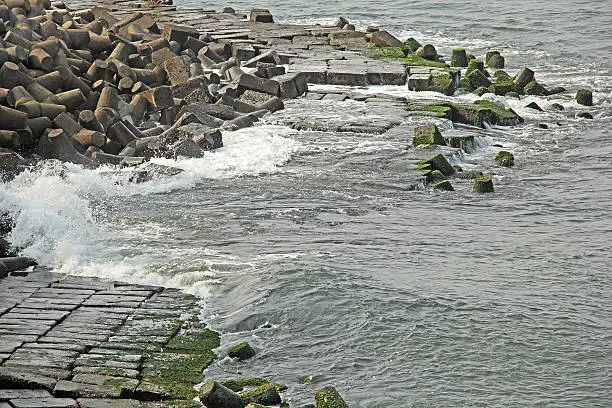 Ocean waves striking on wall made of huge concrete tetrapods and blocks, protecting land from sea erosion in Goa, India