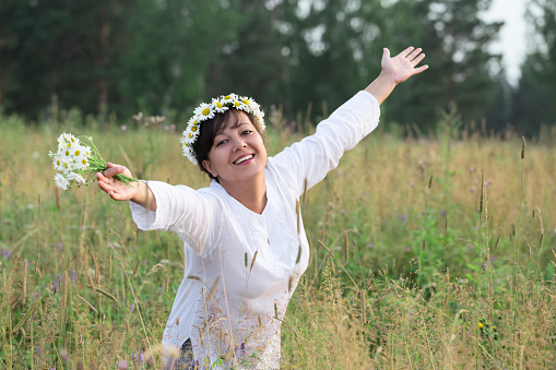Happy young woman with flowers on meadow