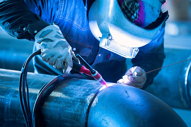 Worker welding metal piping using tig welder Worker welding metal piping using tig welder with protection welding photos stock pictures, royalty-free photos & images