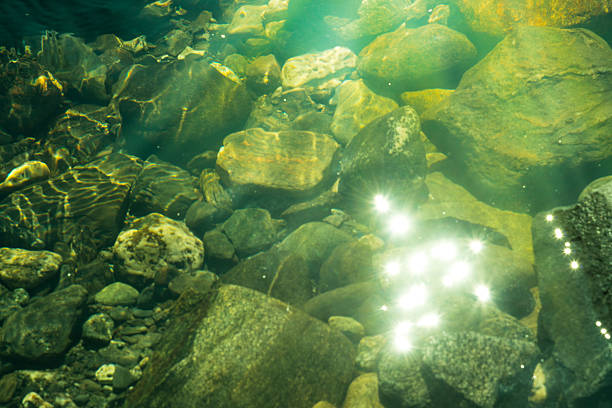 Rippling water with sunbeams and stones in the water
