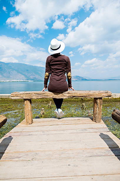 istock Young woman sitting on lakeside jetty 532561850