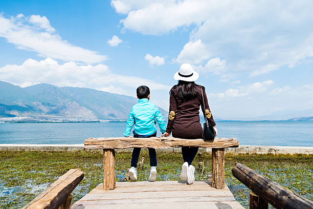 Mother and son sitting on lakeside jetty.