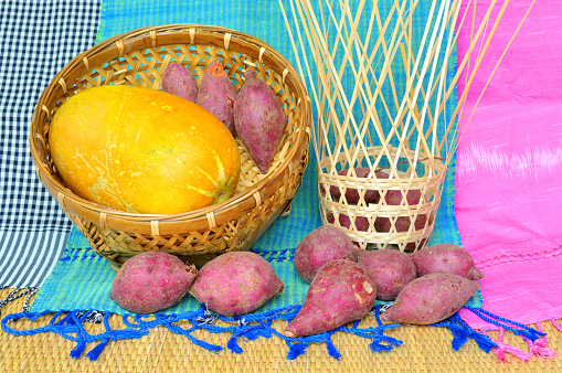 cantaloupe and pile of sweet potatoes on handwoven cotton clothes