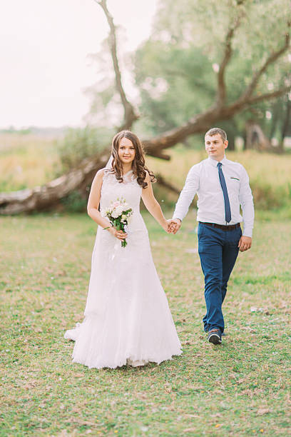 istock Handsome groom and bride in white veil walking back holding 532563918