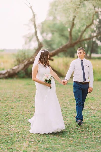 istock Handsome groom and bride in white veil walking back holding 532563978