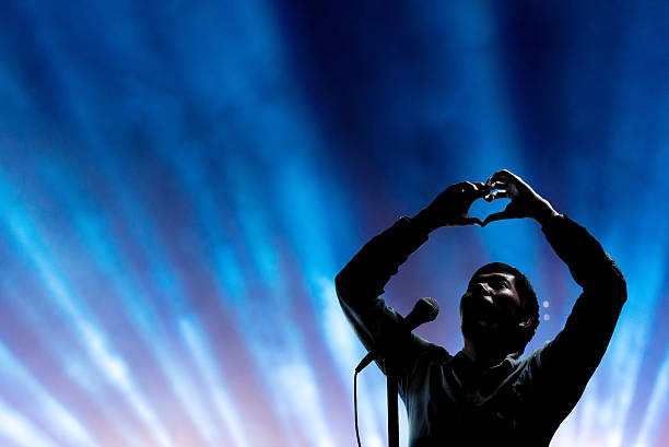 Singer Man posing and singing on concert stage with ray of illuminated