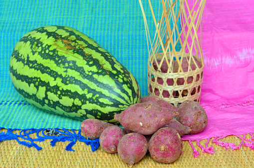 watermelon and pile of sweet potatoes on handwoven cotton clothes