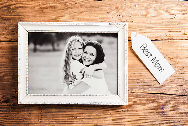 Mothers day composition. Picture frame. Wooden background. Studi Mothers day composition. Photo of mother and daughter in picture frame. Studio shot on wooden background. family photo on wall stock pictures, royalty-free photos & images