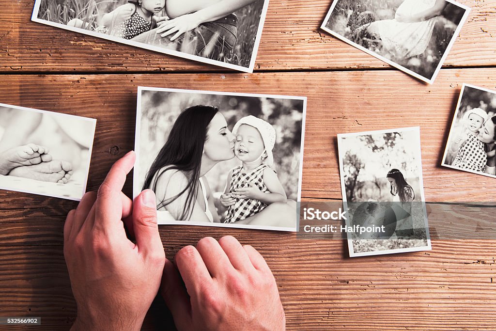 Mothers day composition. Black-and-white pictures, wooden backgr Mothers day composition. Hands of unrecognizable man holding  black-and-white photo. Studio shot on wooden background. Photograph Stock Photo