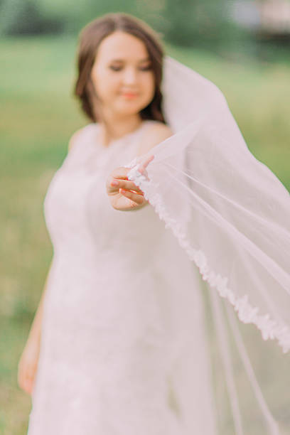 istock Beautiful bride in white dress playing with veil, spring green 532567868