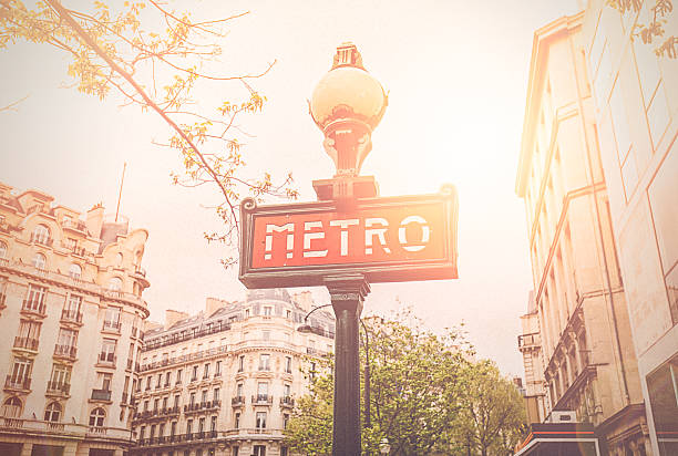 Parisian Metro Sign Parisian metro sign in Paris, France with sunlight effect against French architectural style buildings with rooftops. paris metro sign stock pictures, royalty-free photos & images