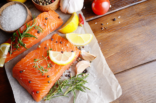 Raw salmon fillet with rosemary pepper sweetbread and salt on baking paper rustic theme with copy-space