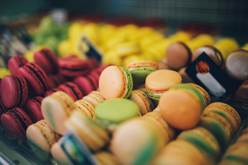 Arrangement of colorful traditional French macaroon sweets in a window. Tasty, sweet food shot in slightly retro vintage film emulated color grading, in shallow focus with a large aperture prime lens.